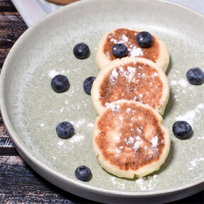 Фото Сладкие сырники из творога с фруктами на сковороде