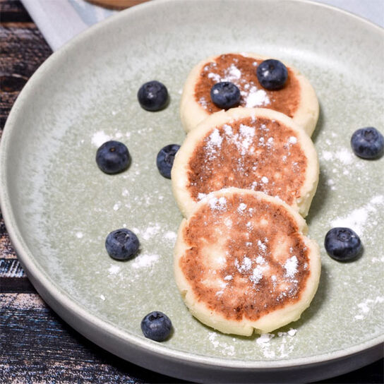 Фото Сладкие сырники из творога с мукой и с фруктами на сковороде